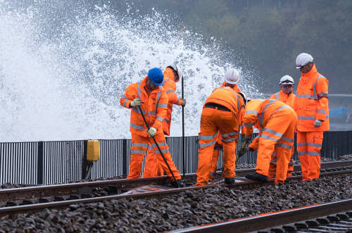 Track ballast shifted by huge waves at Dawlish in Devon after a storm 6th Nov 2018 is being moved back by a maintenance gang of railway workers