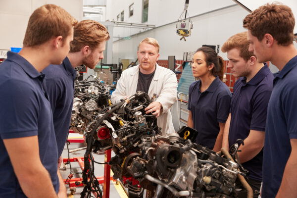 Mechanic,Showing,Parts,Of,An,Engine,To,Apprentices,,Close,Up