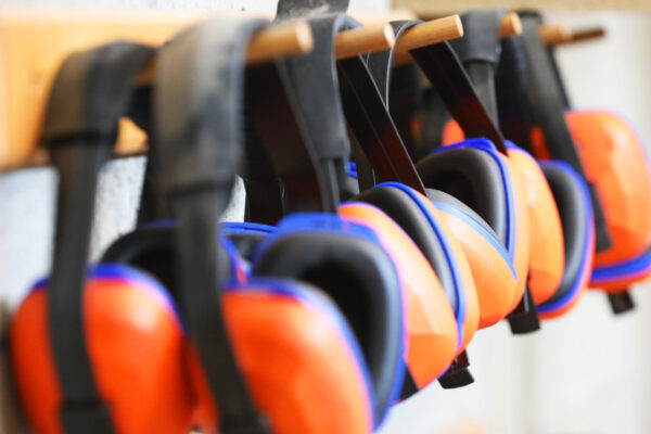 Row,Of,Orange,Ear,Muffs,Ear,Protection,On,A,Rack.